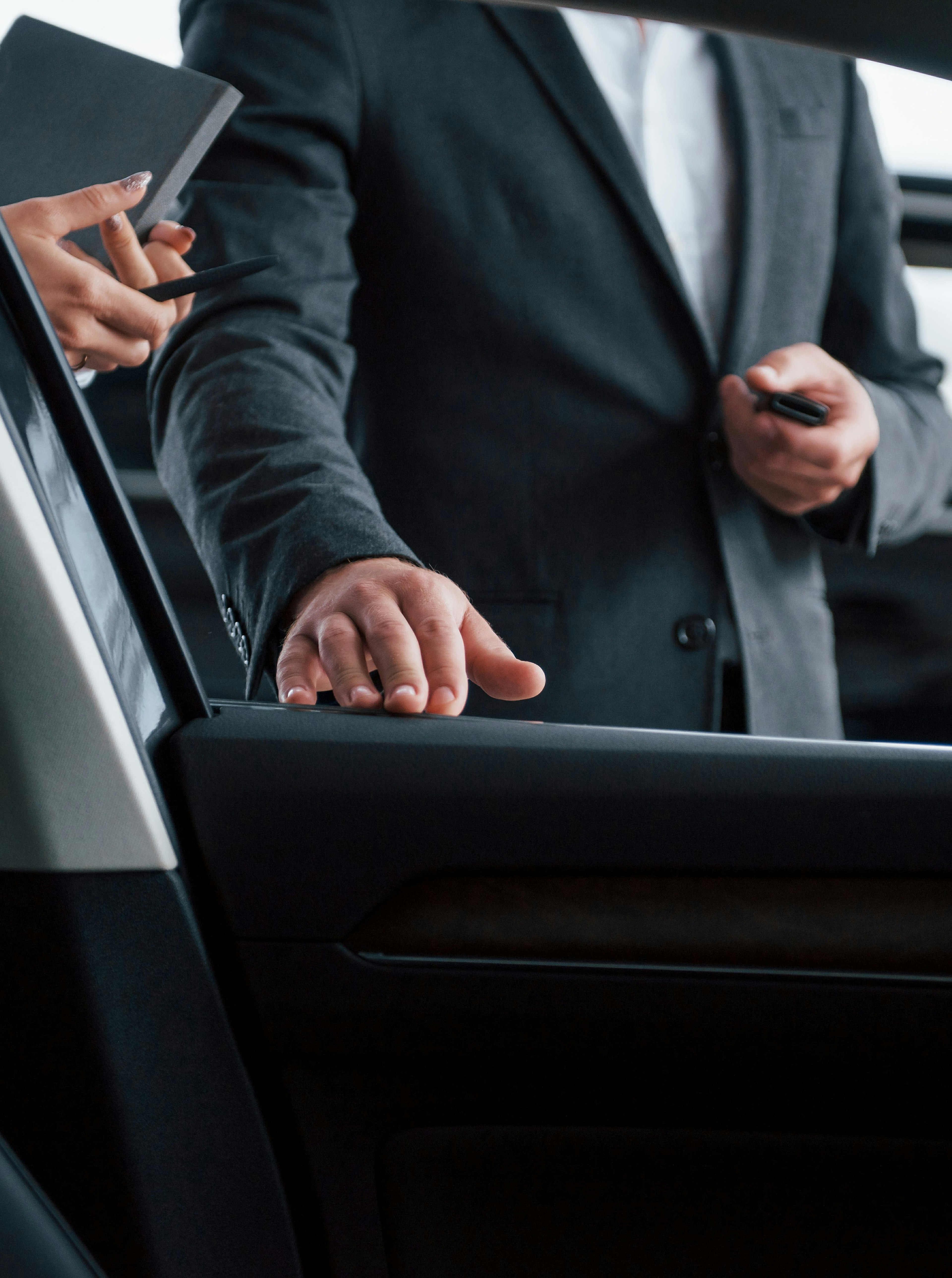 A businessman elegantly entering a black limousine.