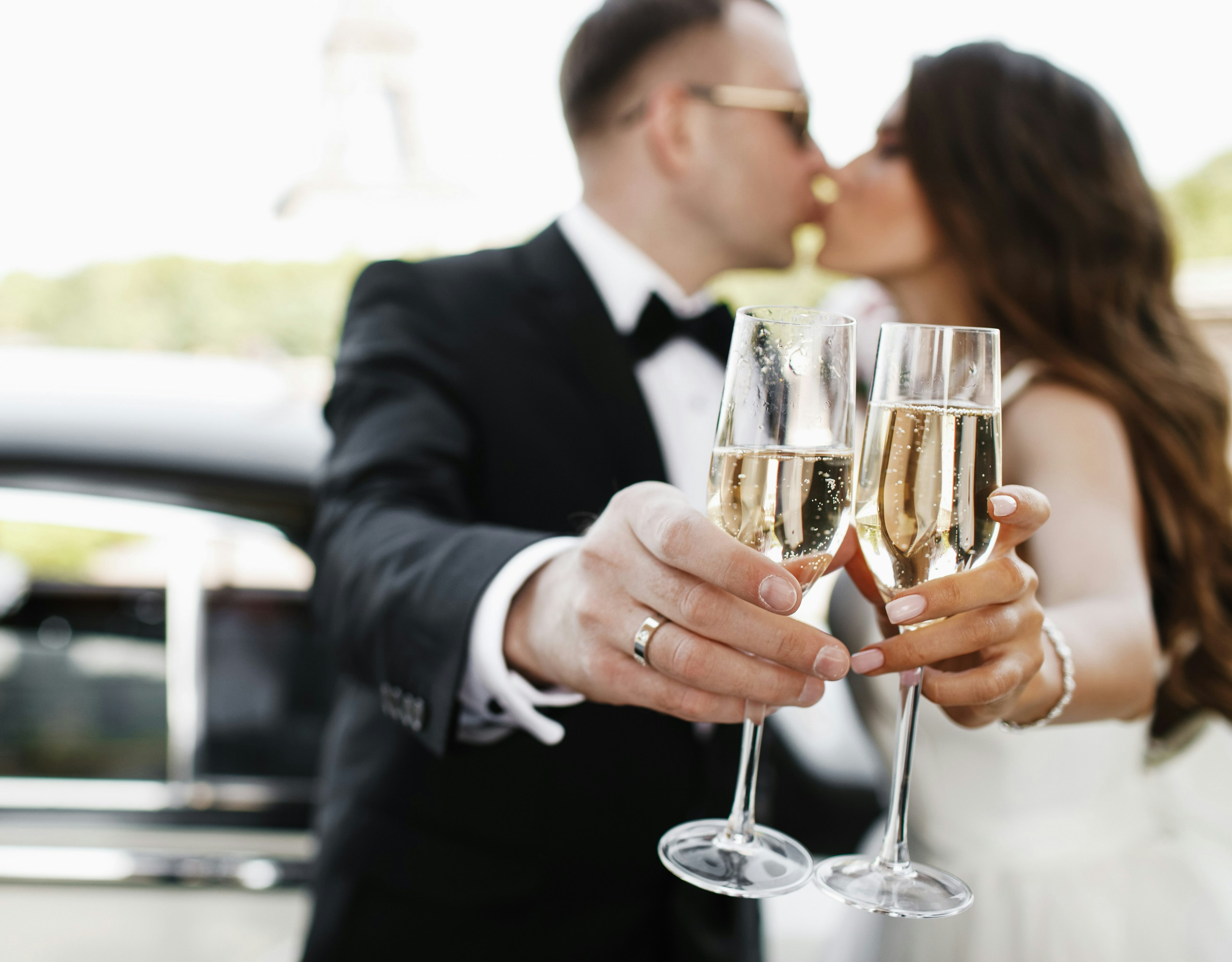 Newlywedds in front of a limo toasting with a chapagne.